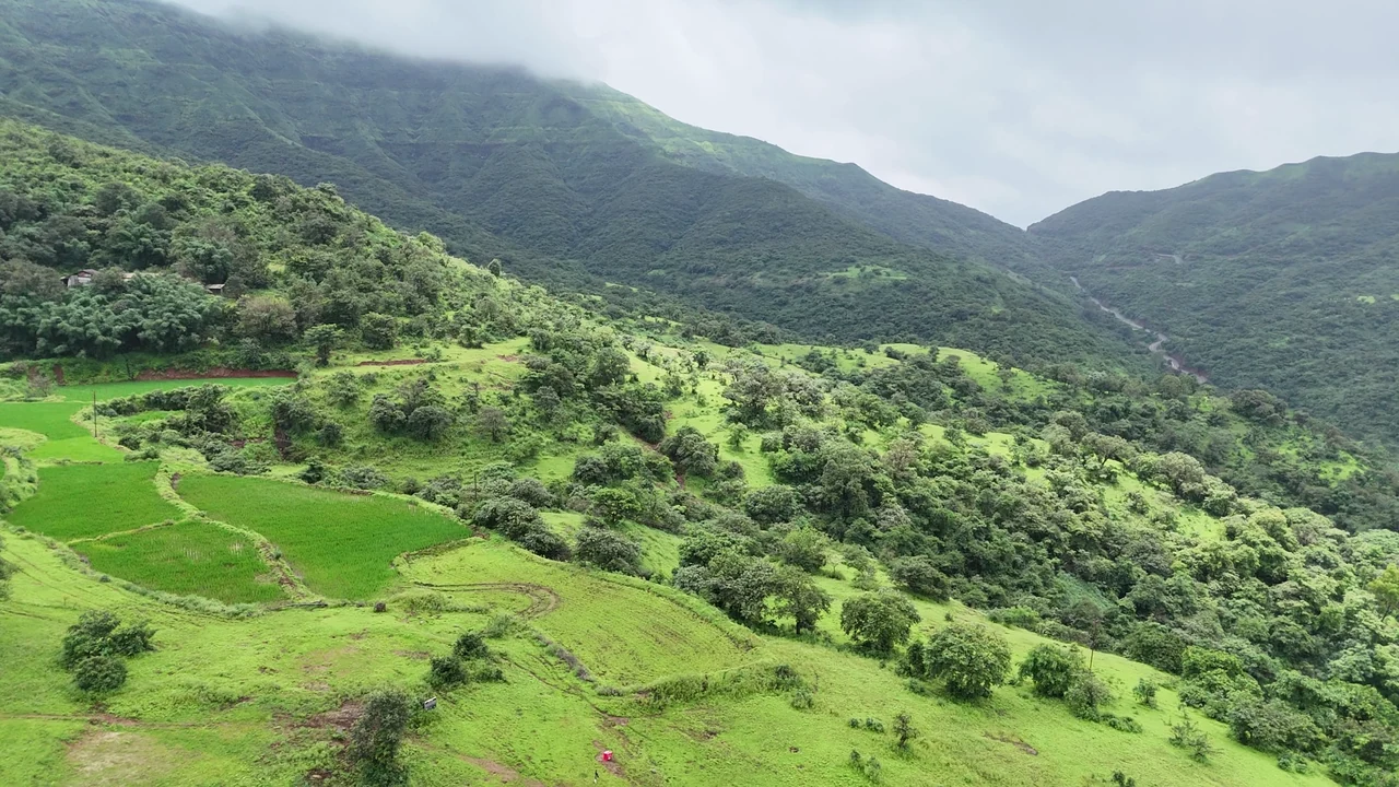 An aerial view of green fields and a valley framed by mountain ridges.