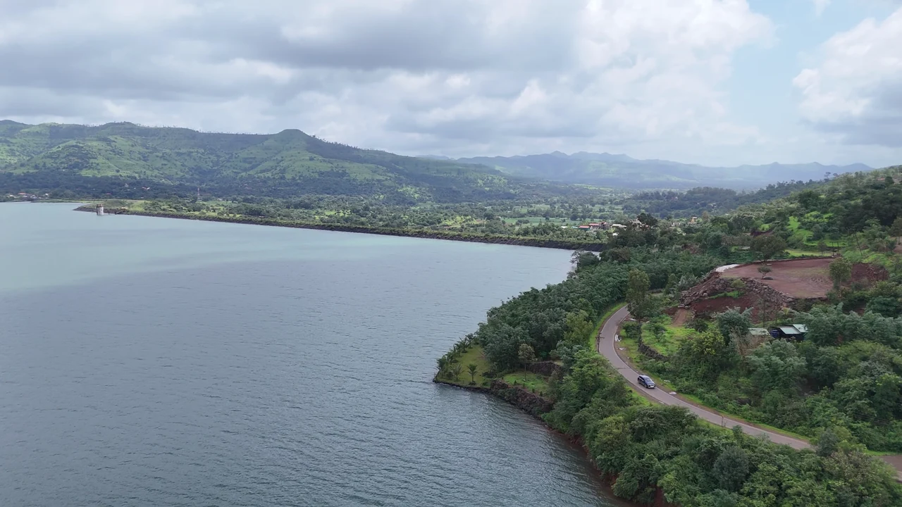 Quiet dam waters curving around a green shoreline beneath the hills.